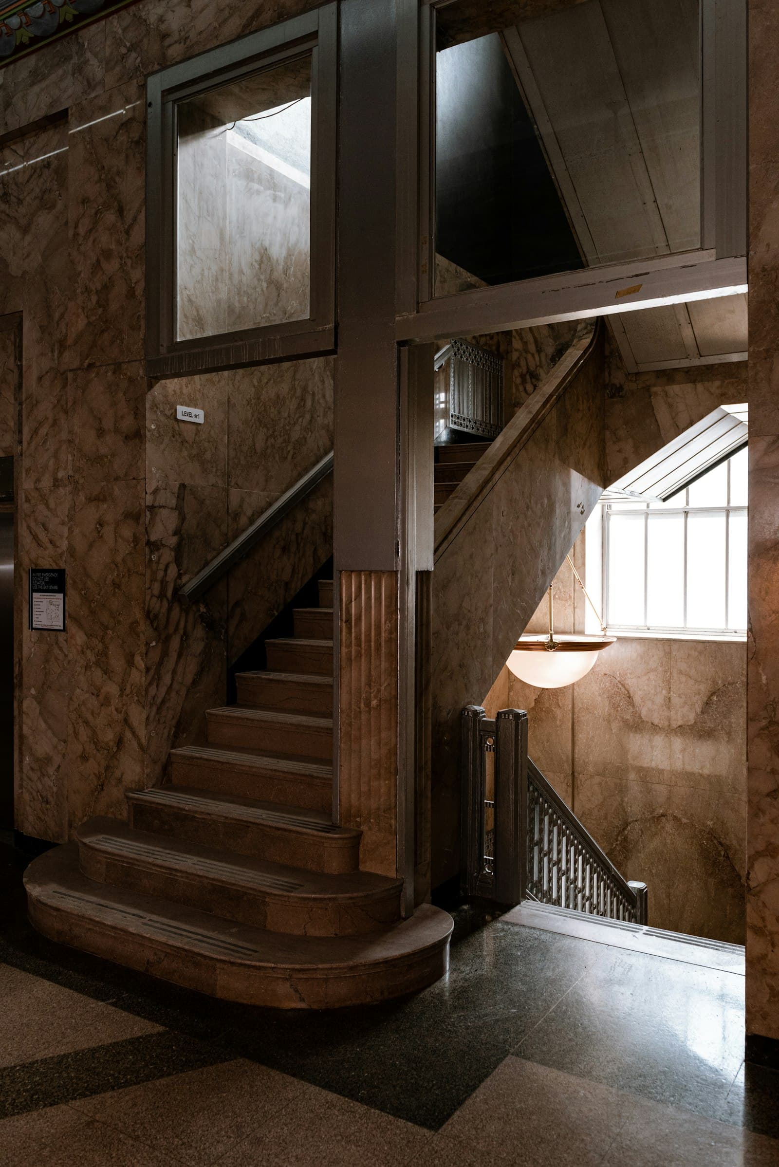 A grand marble staircase ascending through a shadowed interior with rich stone walls