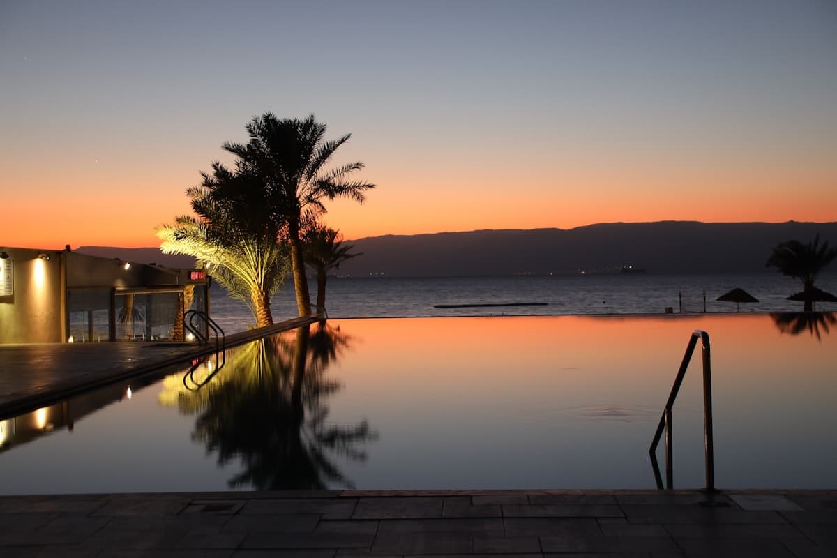 A private infinity pool overlooking the ocean at dusk, still water reflecting the dimming sky
