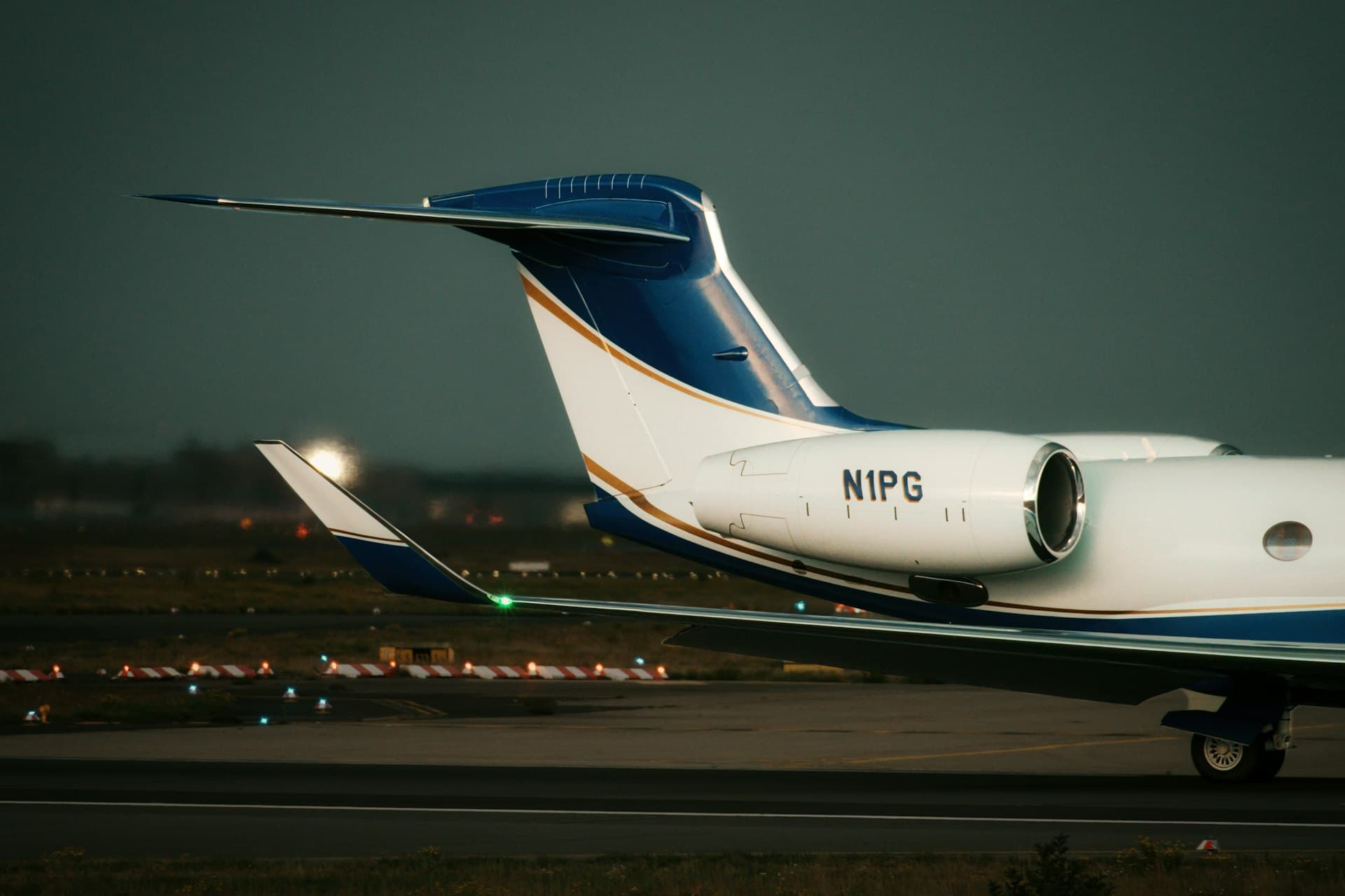 A sleek private jet resting on the tarmac at dusk, its silhouette set against a deep cinematic sky