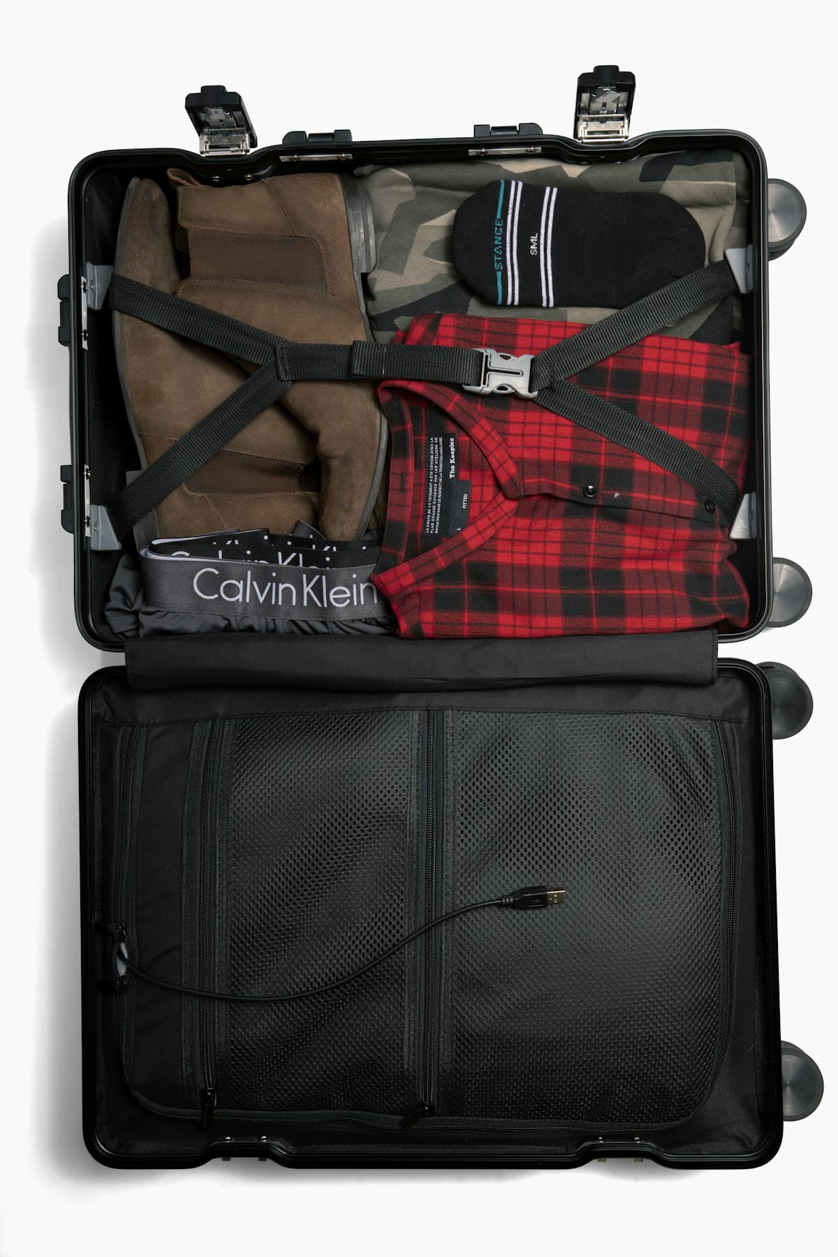 An open travel suitcase neatly packed, photographed from above in moody low light