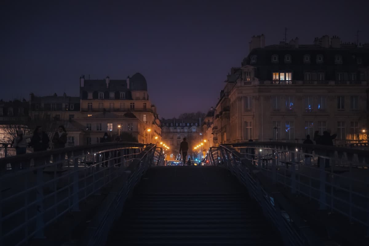 A moody Paris street at night, stone stairs leading up beneath dim city lights