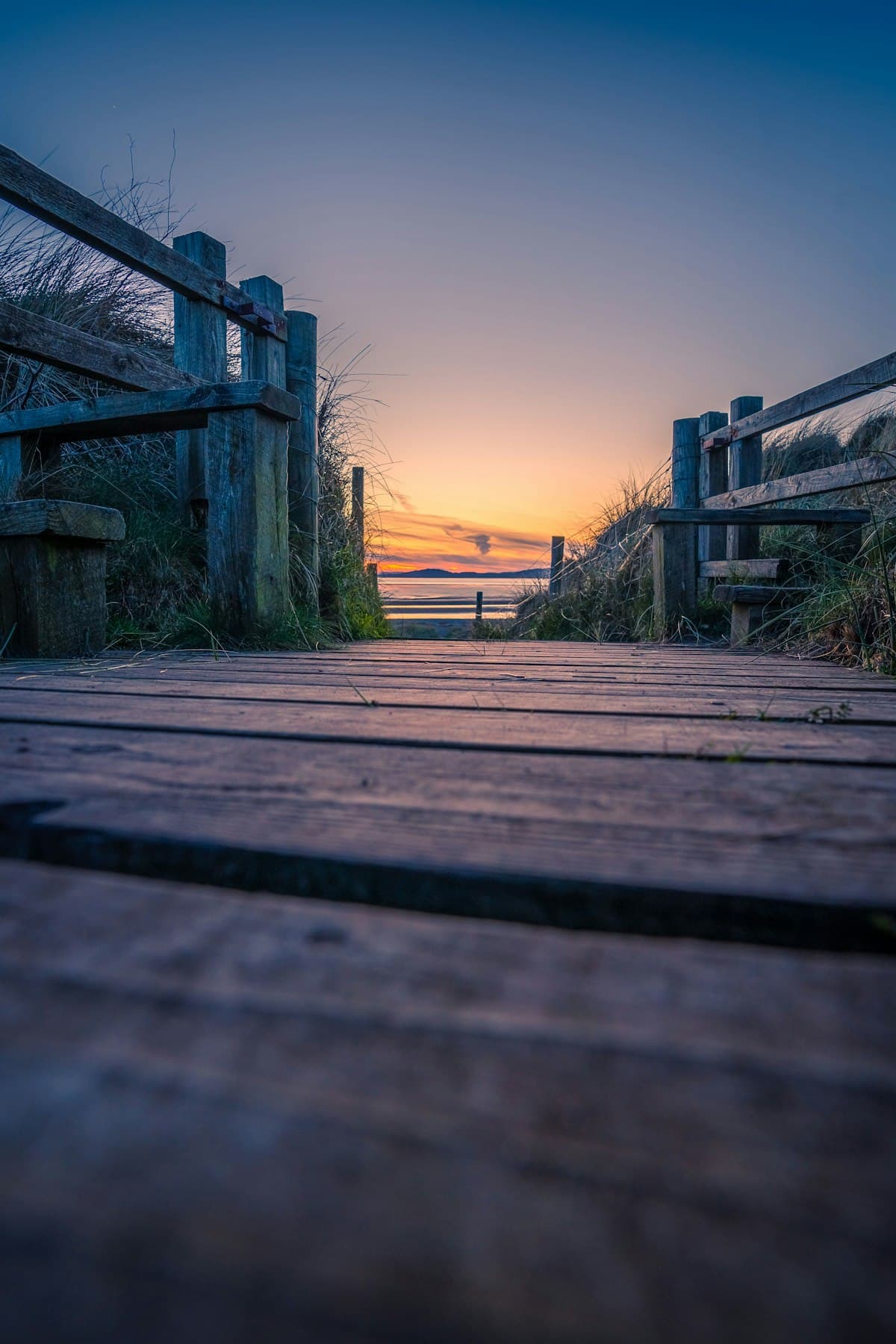 Polished wooden yacht decking stretching toward a calm sea under a fading sky