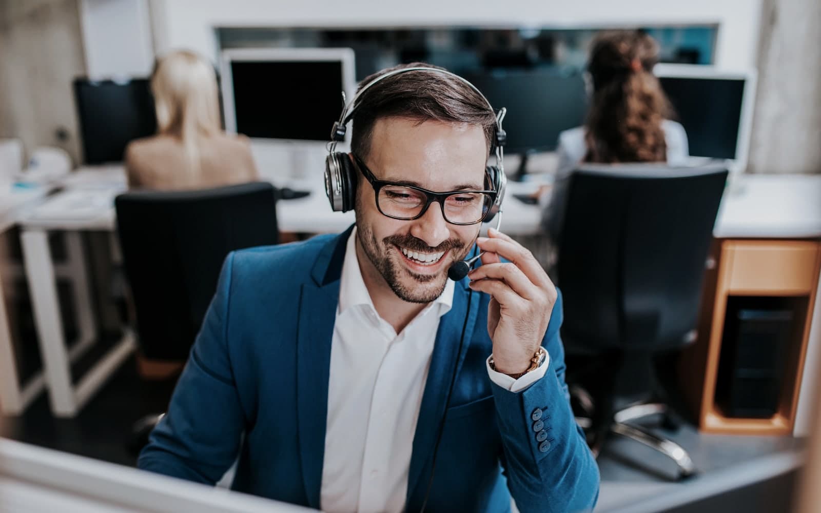 An executive support representative in a tailored suit coordinating by headset from a private operations desk